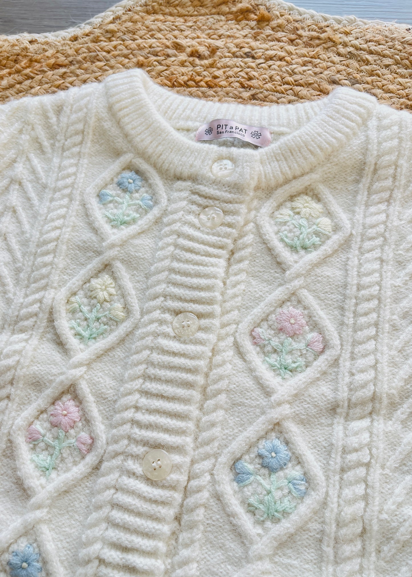 White knitted sweater with crochet flowers.