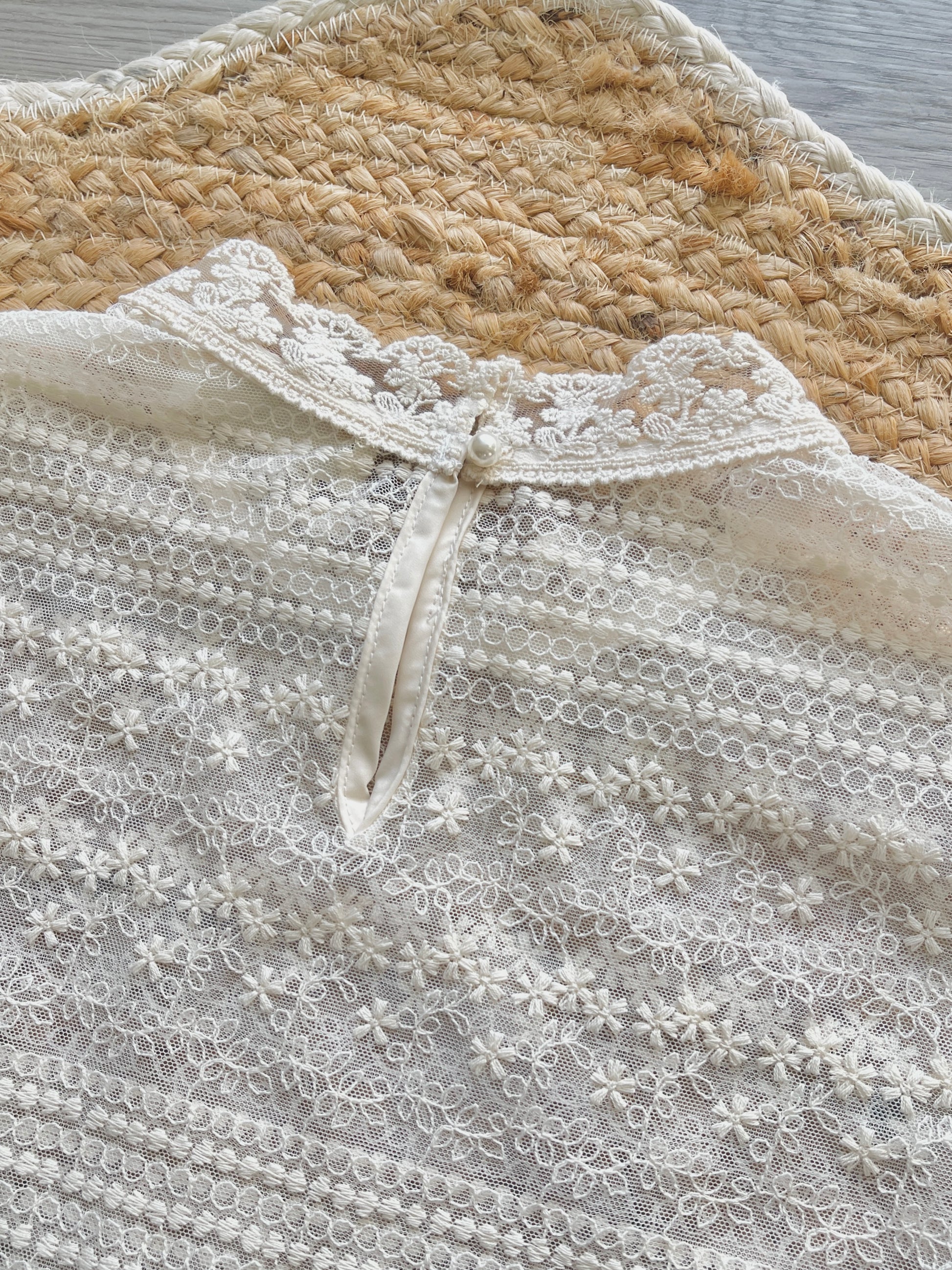 Close-up of a lace garment with keyhole details and pearl button closure