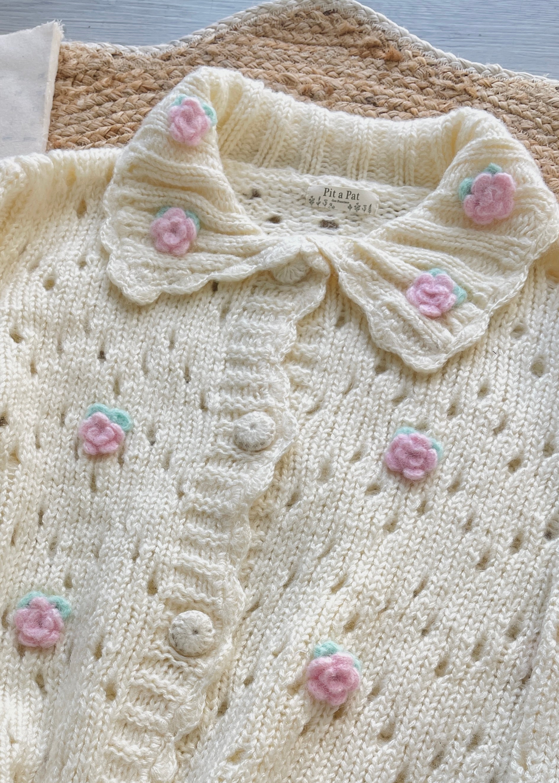 Knitted cardigan with floral embellishments on a textured surface