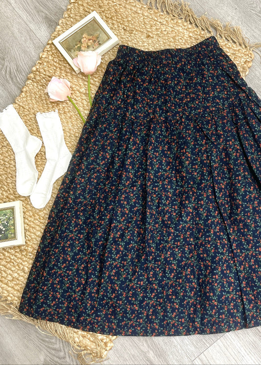 Floral patterned skirt on a woven mat with socks and a photo frame.